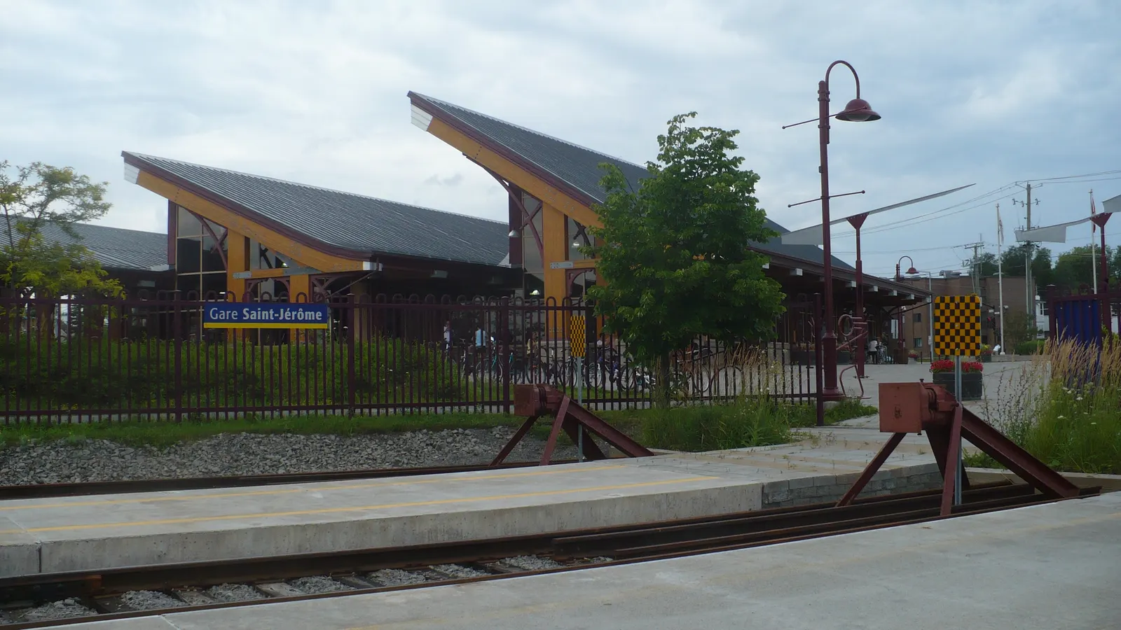 Gare de Saint-Jérôme vue depuis les voies, avec ses toits de bois en pente et le heurtoir rouge au bout du quai